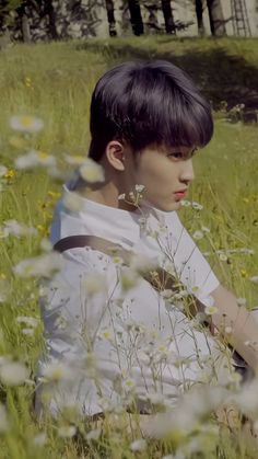 a boy is sitting in the grass with flowers