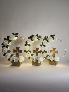 white roses and crosses are arranged in the shape of wreaths with lights around them