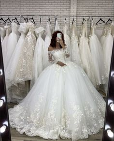 a woman sitting in front of a mirror wearing a wedding dress