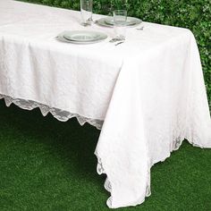 the table is set for two with plates and silverware on it in front of a green wall