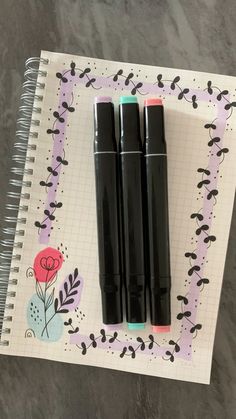 three pens sitting on top of a notebook