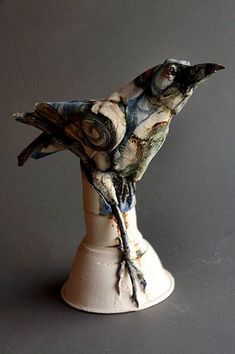 a ceramic bird sitting on top of a white vase