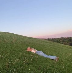 a person laying in the grass on top of a hill