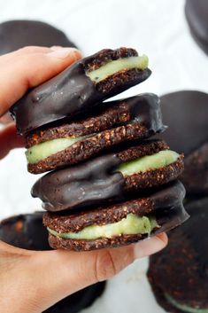 a person is holding up some cookies with chocolate frosting on them and green icing