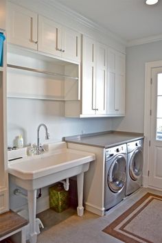 a washer and dryer in a small room with white cabinets on the walls