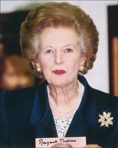 an older woman in a blue suit and pearls holding a sign that says mary grant franklin