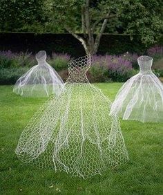 three mannequins in dresses made out of plastic mesh sitting on the grass