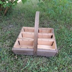 a wooden box sitting in the grass next to a tree