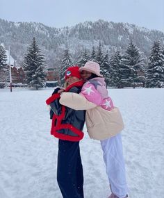 two people standing in the snow hugging each other