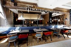 the interior of a restaurant with wooden tables and blue booths, red chairs, and white walls