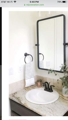 a white sink sitting under a bathroom mirror next to a potted plant on top of a counter