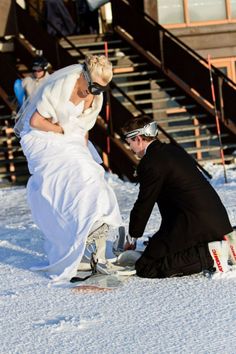 a man kneeling down next to a woman on top of snow covered ground