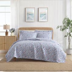 a bed in a room with two pictures on the wall and one has a blue flowered bedspread