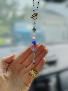 a person holding up a long necklace with charms on it