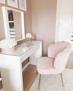 a pink chair sitting in front of a white desk with a mirror on top of it