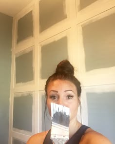 a woman holding up a paint brush in front of her face