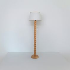 a wooden lamp with a white shade on it's head sitting on a table