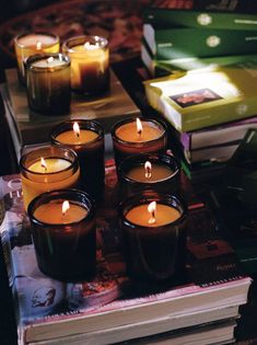 many candles are lit on a table with books