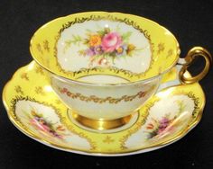 an antique tea cup and saucer with gold trimmings, decorated with flowers