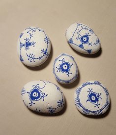 four blue and white painted rocks sitting on top of a table