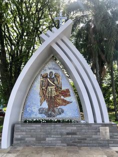 the statue is in front of some trees and bushes, with an angel on it's back