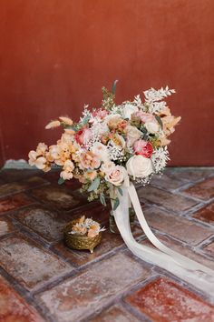 a bouquet of flowers on the ground with a white ribbon