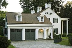 a white house with green garage doors and windows