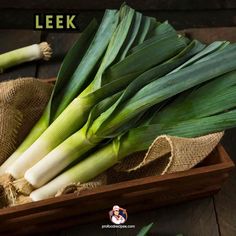 leeks in a wooden box with burlock on the side and two stalks next to it