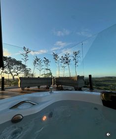 a hot tub sitting on top of a wooden deck next to a tree filled field