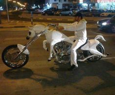 a man riding on the back of a white horse shaped motorcycle in a parking lot