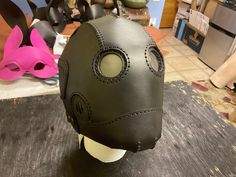 a leather mask is sitting on a table in a room with other masks behind it