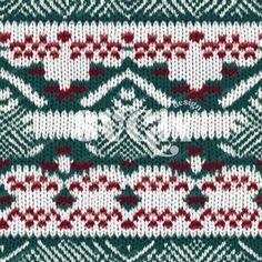 a green and white knitted sweater with red flowers on the bottom, in an ornate pattern