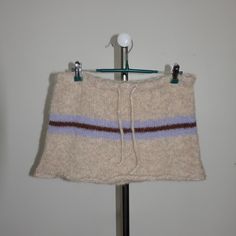 a sweater hanging on a clothes rack in front of a wall with a coat hanger