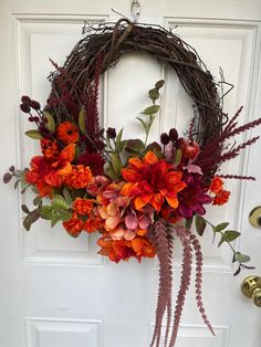 a wreath with flowers hanging on the front door