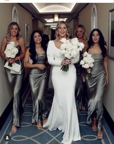 the bride and her bridesmaids are all dressed in silver dresses with white bouquets