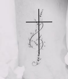 a cross tattoo on the back of a woman's neck, with flowers growing out of it