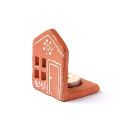 a small clay house with a candle in the center on a white background, it appears to be made out of clay