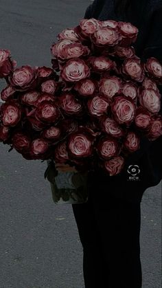 a person holding a bunch of flowers in their hands on the street with no one around