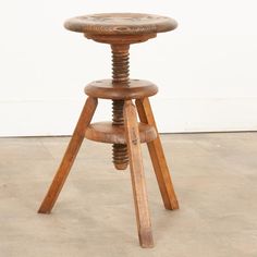 an old wooden stool sitting on top of a cement floor next to a white wall