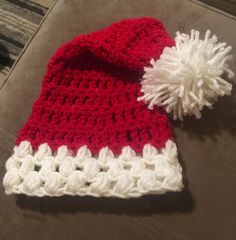 a red and white crocheted hat with a pom - pom