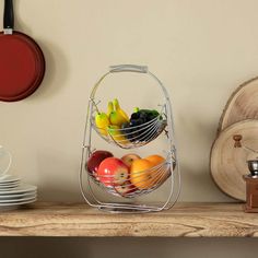 two metal baskets filled with fruit sitting on top of a wooden table next to plates