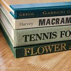 four books stacked on top of each other in different colors and sizes, sitting on a wooden table