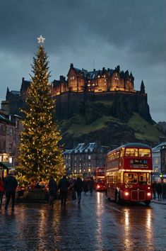 a christmas tree is lit up in front of edinburgh's old royal castle and the famous red double decker bus