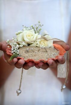 a person holding a small piece of sand with flowers on it in their hands,