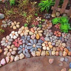 rocks arranged in the shape of a heart on top of a rock garden path with plants and flowers