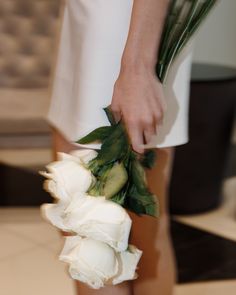 a close up of a person holding flowers in one hand and an object in the other