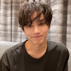 a young man sitting on top of a couch wearing a black shirt and smiling at the camera