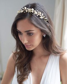 a woman wearing a white dress and a gold headpiece with flowers on it's side