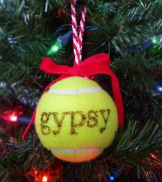 a tennis ball ornament hanging from a christmas tree with the word gyppsy written on it