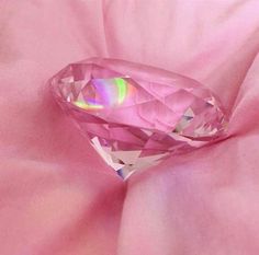 a pink diamond sitting on top of a pink sheet covered in shiny foil and fabric